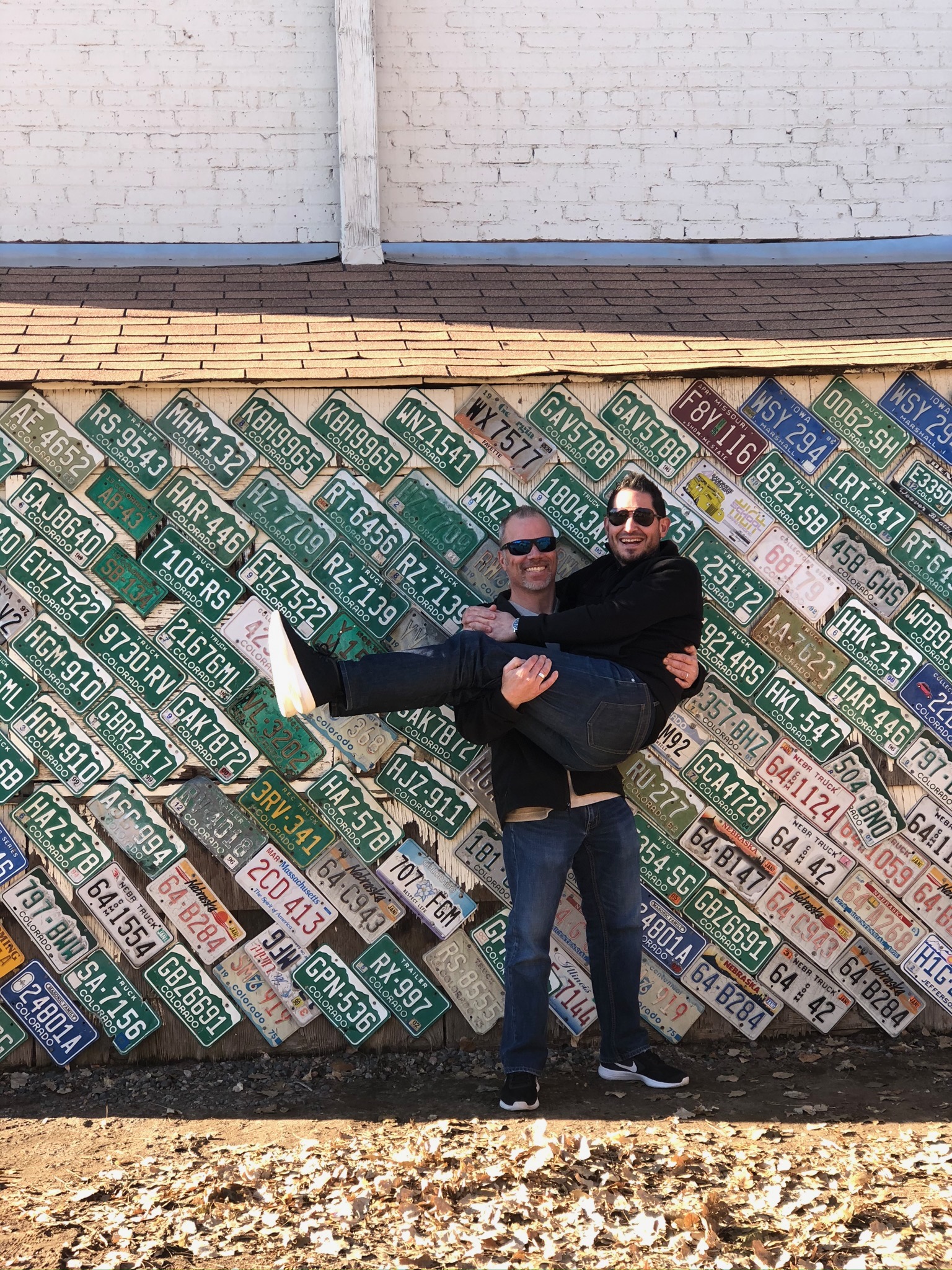 Badd Jadd holding Martin in front of a wall of license plates